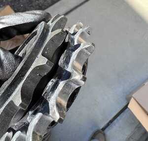 Comparing a worn front sprocket and a new front sprocket side by side. Wear on the old sprocket is clearly visible