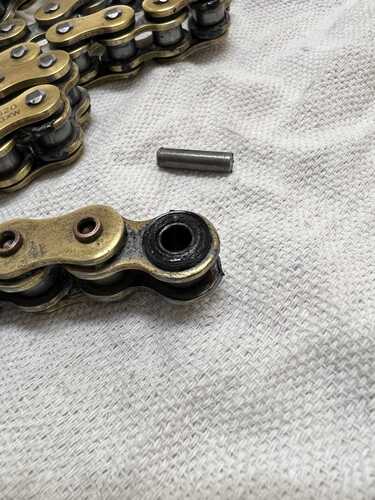Broken chain lying on cloth with separated link, o-rings, and extracted pin visible