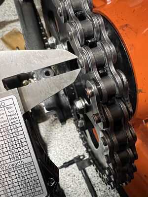 Shows a caliper being used to measure a factory riveted chain pin.