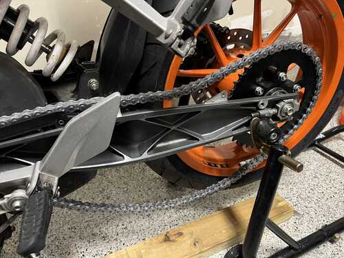 Showing the new chain mounted on the motorcycle. It is much too long and hangs loosely.